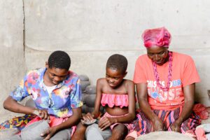 three women and children sitting on the ground